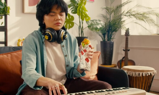 A man on his keyboard with a KFC Twister on hand