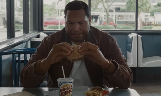 A screenshot from Burger King's latest campaign "There's a New King and It's You" showing a female employee holding a signature Burger King crown