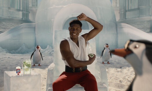 A man lifting his arm up while surrounded by penguins
