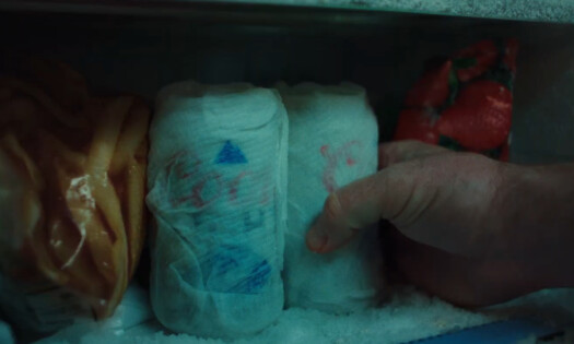 Two cans of Coors Light wrapped in tissue paper in a freezer