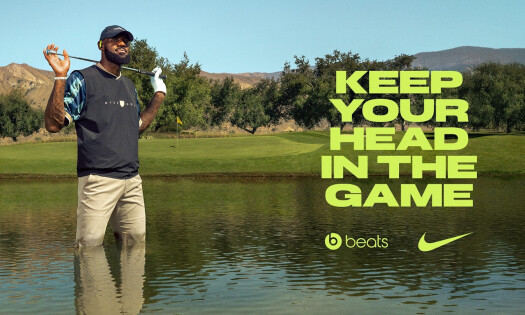 LeBron James wearing the Nike Powerbeats Pro 2. while standing in knee-deep water at a golf course's pond