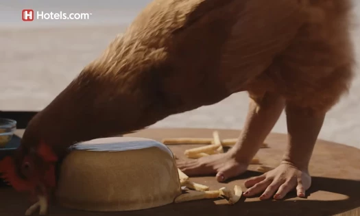 A chicken on a table with hands for its feet to literalize the phrase "chicken fingers"