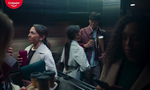 A woman in an elevator smiles at a man across from her