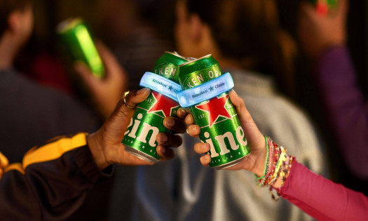 Arms holding two clinking Heineken cans with The Clinker attached