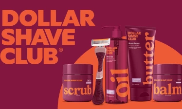 Dollar Shave Club women’s grooming line featuring razor, shave oil, butter, scrub, and balm in bold maroon and orange packaging against a branded background.