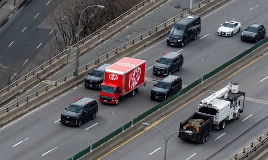 A photo of a KitKat branded truck, escorted by convoy vehicles, driving across a Toronto highway