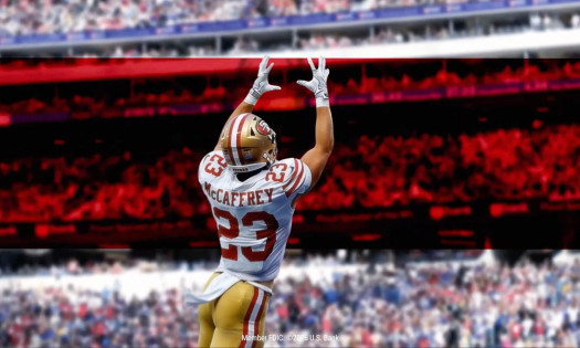 McAffrey with his back to the camera as he jumps up to catch a football with U.S. Bank's signature red stripe