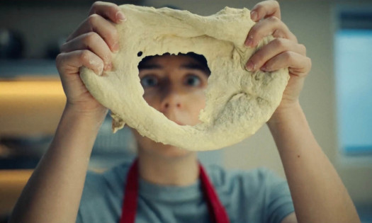 A Papa Johns employee looking through a hole in a failed sourdough base