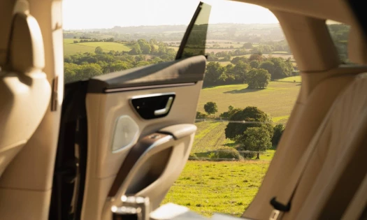 A luxury car opens to the scenic sight of a British countryside