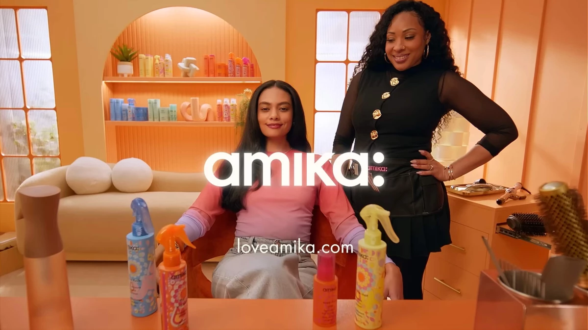 Amika's "On Your Wavelength" product range on display in a salon, with a stylist's hand picking up one product.
