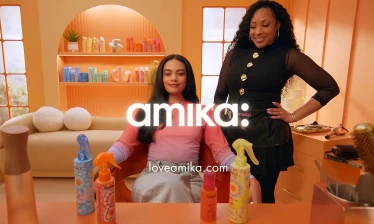 Amika's "On Your Wavelength" product range on display in a salon, with a stylist's hand picking up one product.