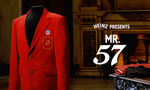 Red blazer displayed on a mannequin featuring an NFL patch and "Mr. 57" crest, set in a formal interior with a fireplace, alongside the text "Heinz Presents Mr. 57."