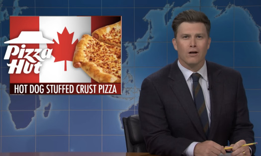 A screenshot from SNL showing Colin Jost poking fun at Pizza Hut Canada's hot dog stuffed crust