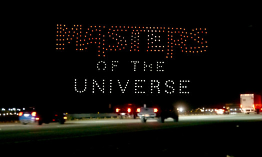 "Masters of the Universe" written in a drone display across the night sky over traffic congestion.