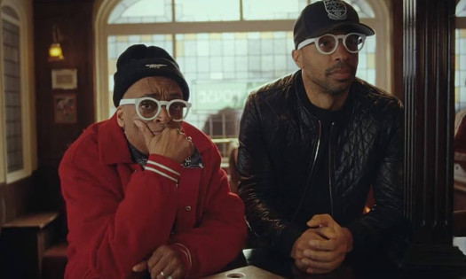 Spike Lee and Thierry Henry staring off camera seated at a bar.