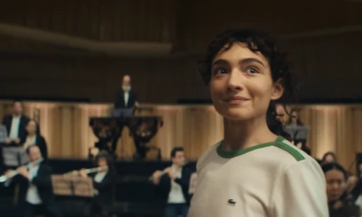A young woman in the middle of an orchestra sporting a Lacoste shirt