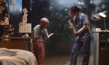 A nurse watches a kid draw Disney characters on a fogged up window