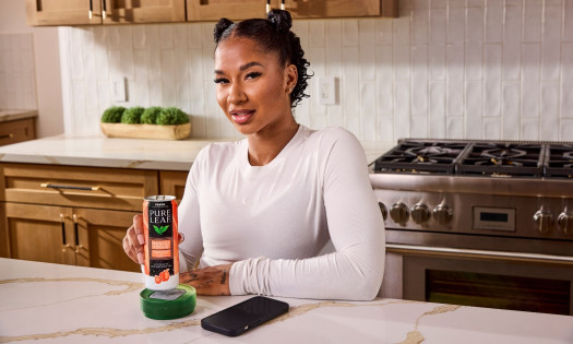 Jordan Chiles holding Pure Leaf Mental Focus Ice Tea peach flavor, over the custom coaster "Mental Focus Dock" and embedded Brick device.