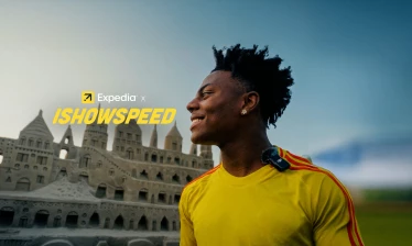 IShowSpeed staring out with a historical building in the background. Expedia x IShowSpeed typography sits the left of his gaze.
