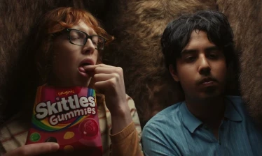 A man and a woman eating Skittles Gummies