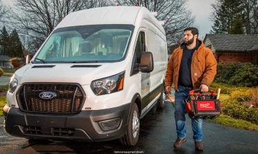 Worker standing next to white Ford van.