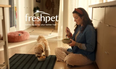 Woman eating with her dog on the kitchen floor