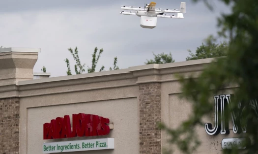 A Wing drone flying over a Papa Johns restaurant.