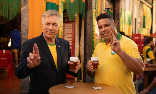 Carlo Ancelotti and Ronaldo Nazário hold Brahma beers outside a Brazil-themed bar in Brahma’s FIFA World Cup 26 campaign.