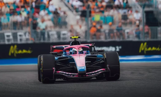 BWT Alpine Formula One car racing on track in front of spectators during a Grand Prix weekend.