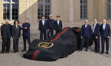F1 racing car in Gucci branded cover, surrounded by brand management.
