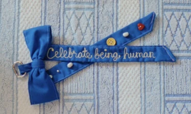 Crafted blue bow with "Celebrate being human" embroided on it.