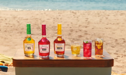 Hennessy Very Special Cocktails bottles and served drinks displayed on a beach table.