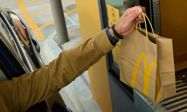 A hand reaching for a Mcdonald's paper bag at a drive thru in Texas