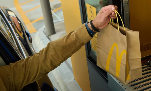 A hand reaching for a Mcdonald's paper bag at a drive thru in Texas