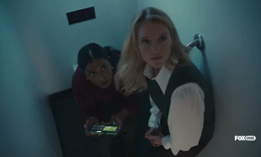 Two women hiding inside a cubicle to watch football