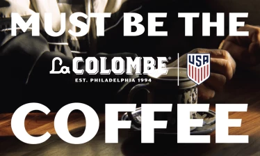 A hand holds a coffee cup beneath the words “Must Be the Coffee,” alongside the La Colombe and U.S. Soccer logos.