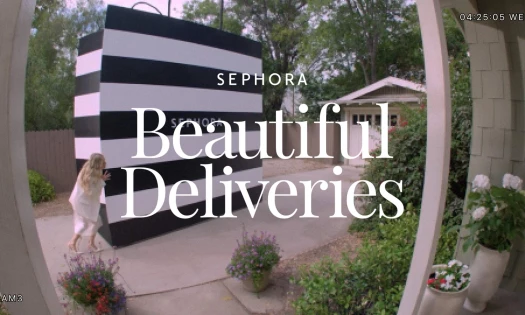 Molly Sims pushing a giant Sephora delivery bag across a driveway caught from the POV of a door cam.