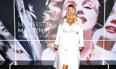 A woman standing in front of the "Manifesting Marilyn: The Making of an Icon" event board