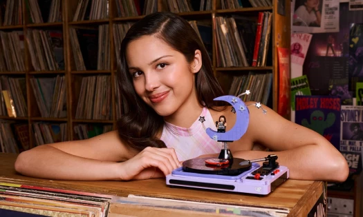 Olivia Rodrigo with the concert moon LEGO recreation from her tour visuals in a record store.
