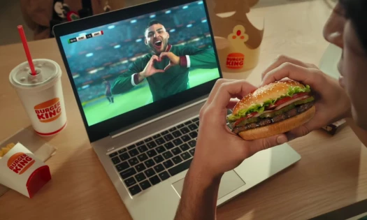 A man watching a football game while holding the Whopper