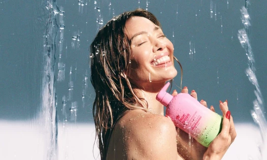 Hilary Duff under a water shower holding a Fruit Fusion body wash from Bath & Body Works.