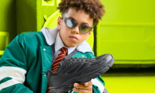 A kid holding up a Clarks shoe