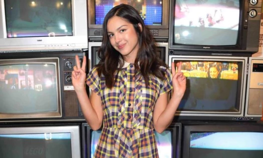Olivia Rodrigo posing in front of vintage television boxes
