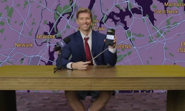 Kyle Cooke behind a weather reporter's desk