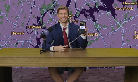 Kyle Cooke behind a weather reporter's desk