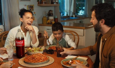 A family eating dinner with a bottle of Coca-Cola