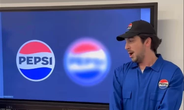 Two men in Pepsi branded overalls and baseball caps. One is wearing sunglasses.