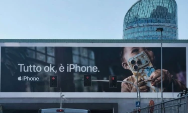 OOH billboard showing a toddler holding a food covered iPhone with the Italian caption, "Tutto ok, è iPhone" Apple iPhone logo sits underneath.