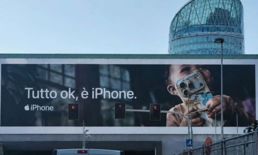 OOH billboard showing a toddler holding a food covered iPhone with the Italian caption, "Tutto ok, è iPhone" Apple iPhone logo sits underneath.