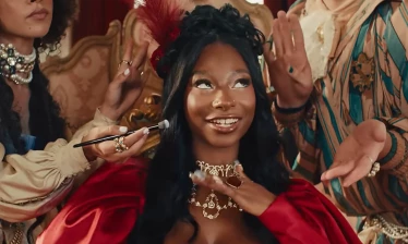 Trinity Tatum surrounded by people applying make up on her